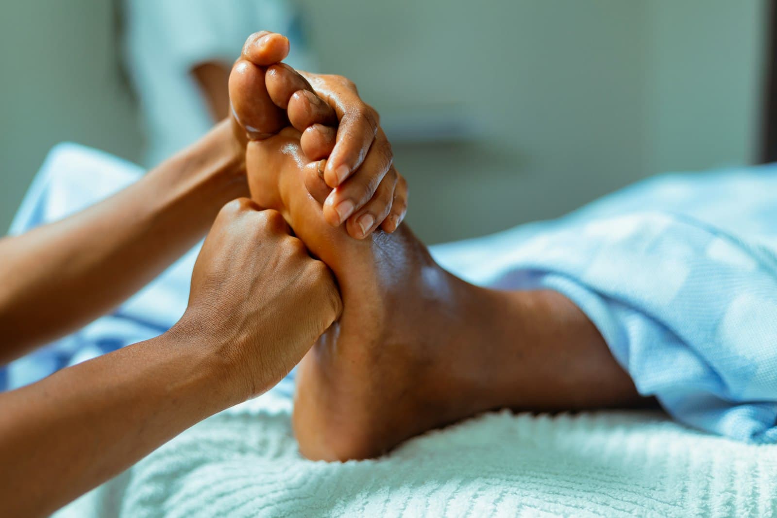 Hands massaging a foot with oil