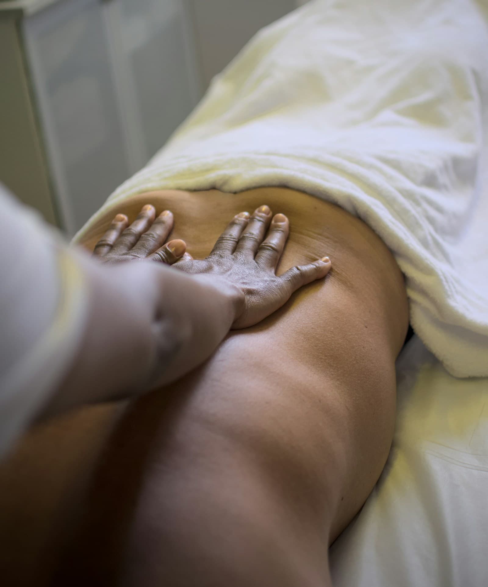 A hand resting flat against a person's lower back